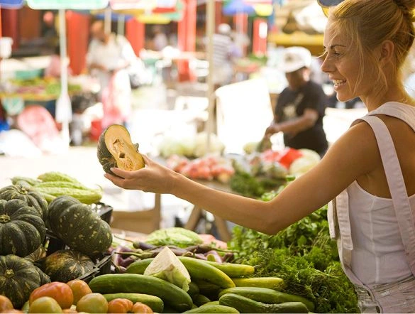 a person shopping at a market holding a squash