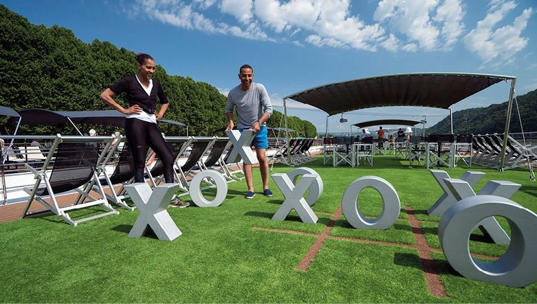 Friends playing a game of noughts and crosses on the Sun Deck of a luxury river ship on a bright day