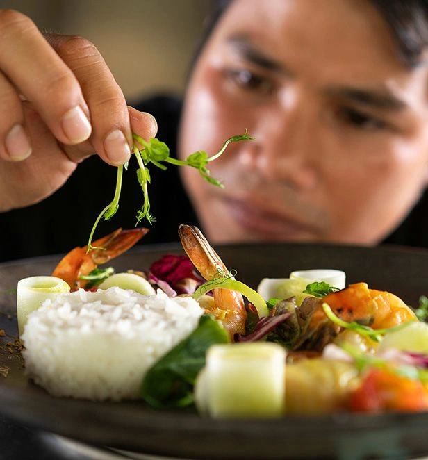 A Chef preparing a plate of food on the Scenic Spirit ship.