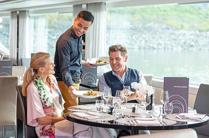 A man and woman being served plates of food at Crystal Dining on board a Scenic cruise ship in Budapest, Hungary.
