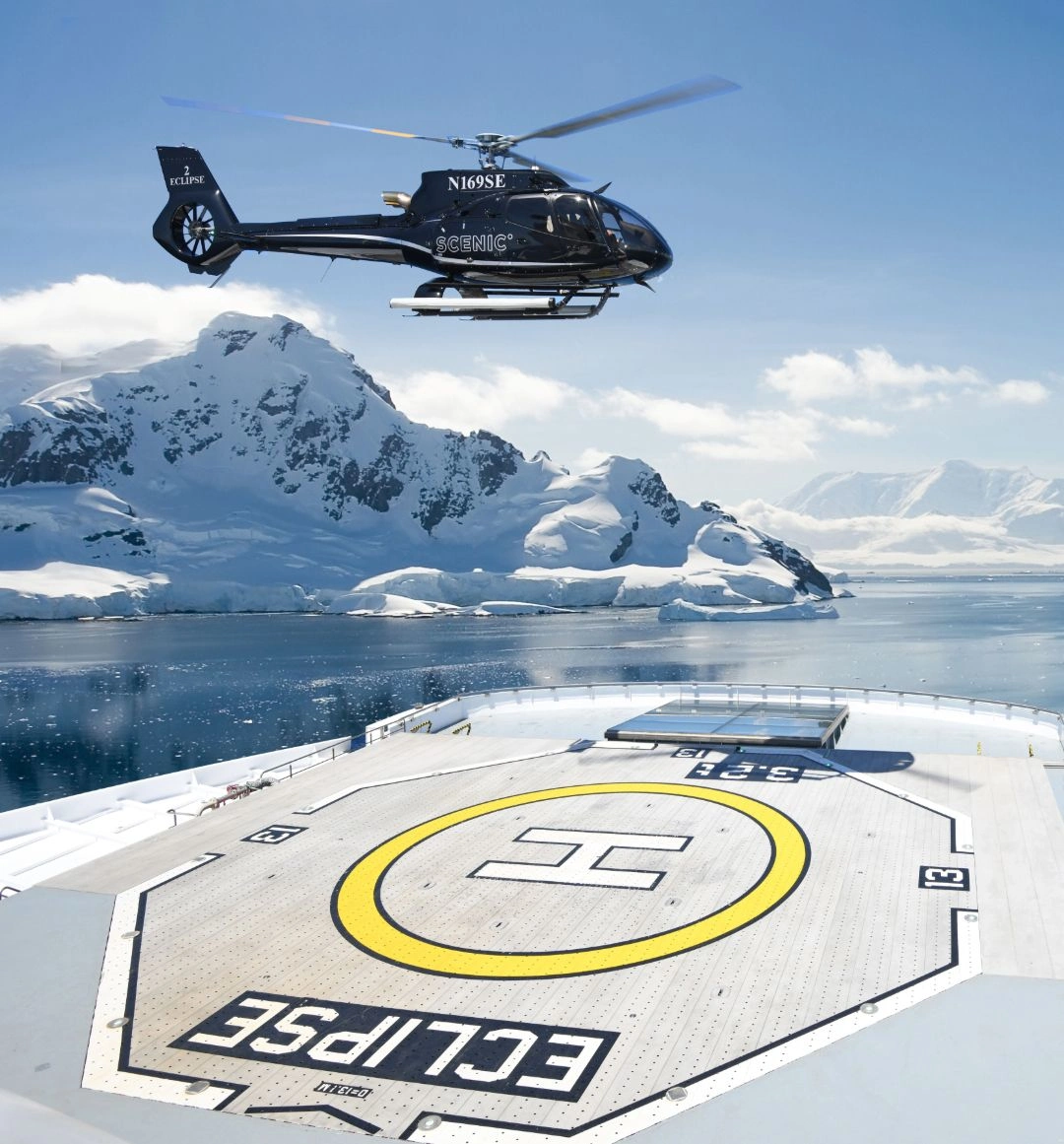 The helicopter aboard Scenic Eclipse hovers above a vast expanse of ice, showcasing the stark beauty of the frozen landscape below.