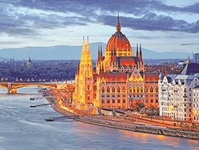 : Hungarian Parliament Building lit up at night next to the Danube River in Budapest, Hungary