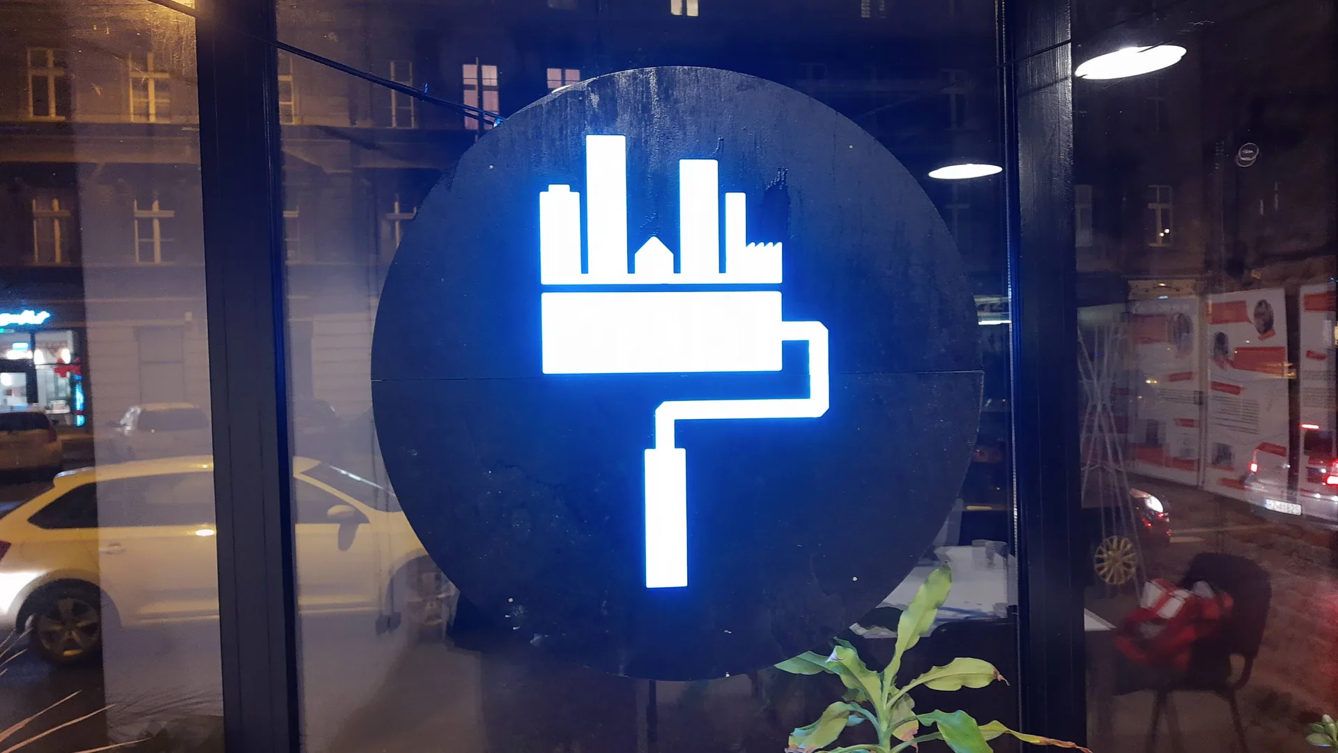 Logo Fundacji Napraw Sobie Miasto - wałek malarski z miastem - na witrynie siedziby przy ul. Warszawskiej 56 w Katowicach