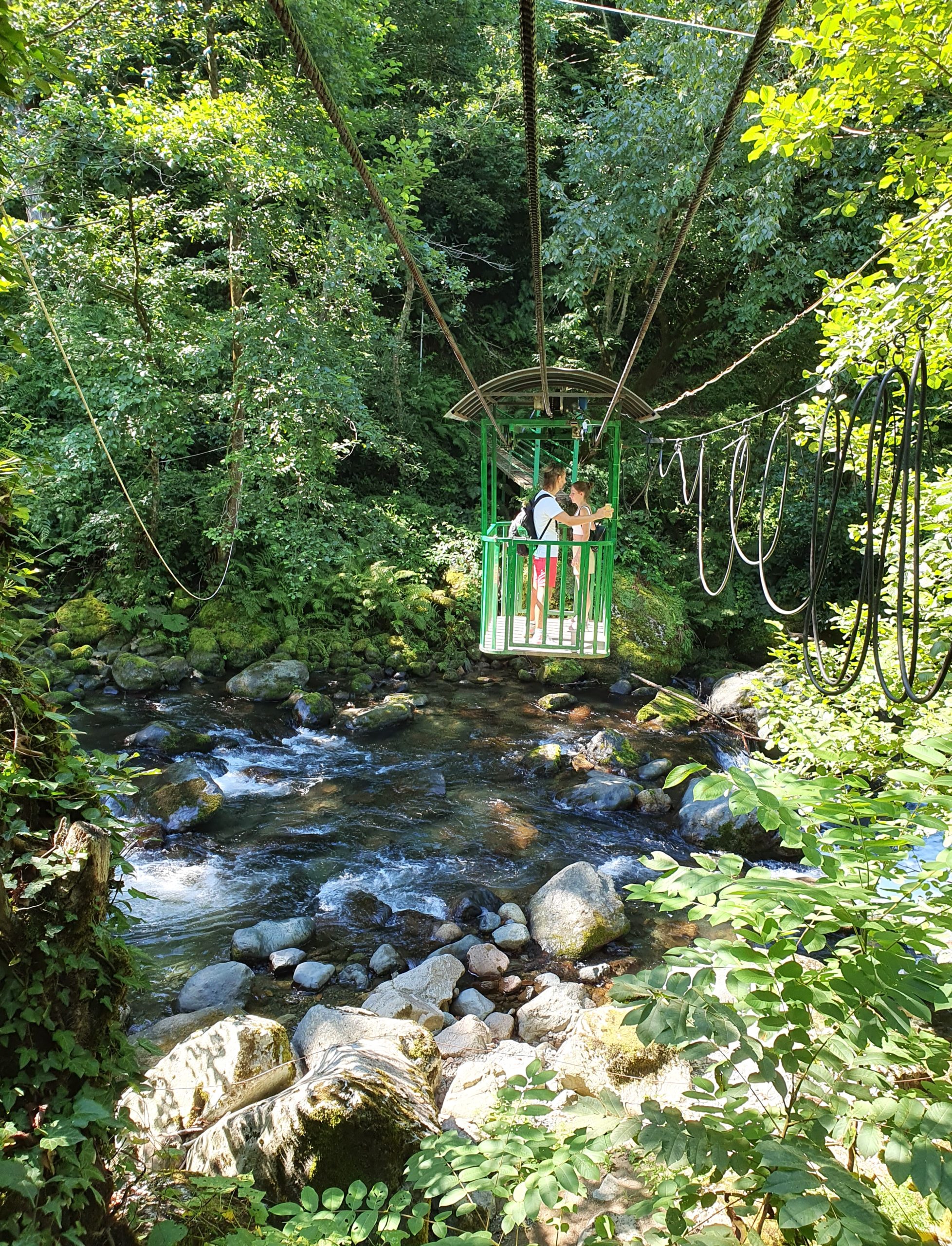 посетители передвигаются по канатной дороги через реку