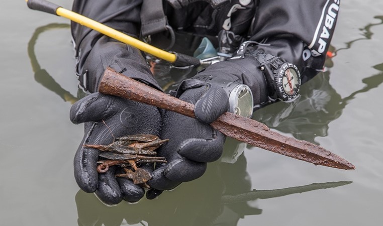 водолаз держит находки в руках