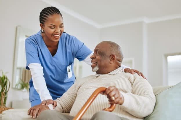 A smiling adult-gerontology acute care nurse practitioner speaks with a patient.