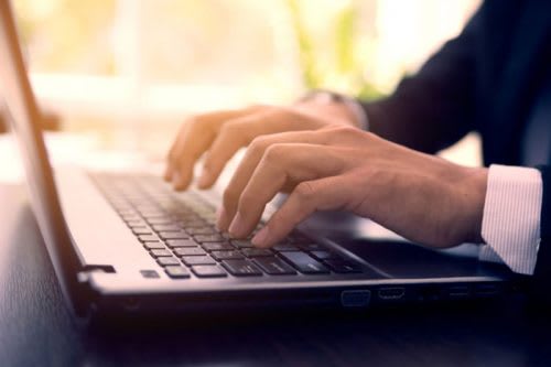 Male hands in a suit typing on the laptop