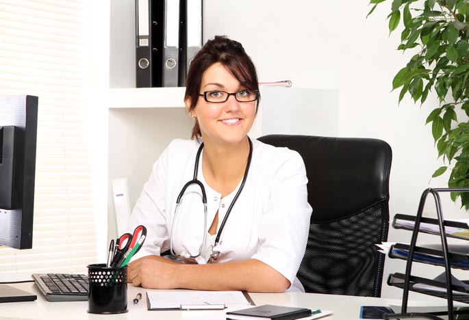 A smiling DNP sits behind a desk.