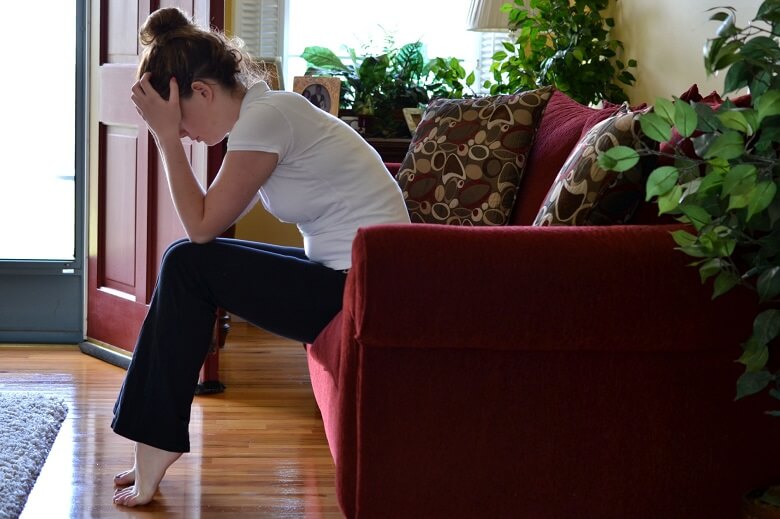 Woman feeling stressed on edge of couch