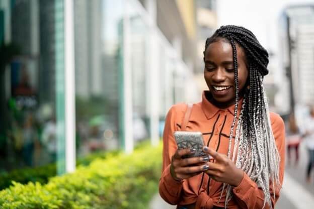 A smiling person using a mental wellness app on a smartphone.
