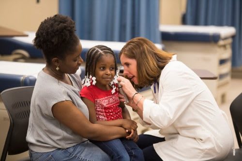 A nurse practitioner examines a young child.
