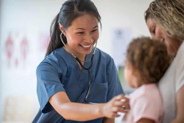 A family nurse practitioner smiles at an infant patient.