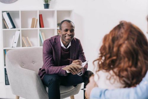 Counselor smiling while talking with a couple.