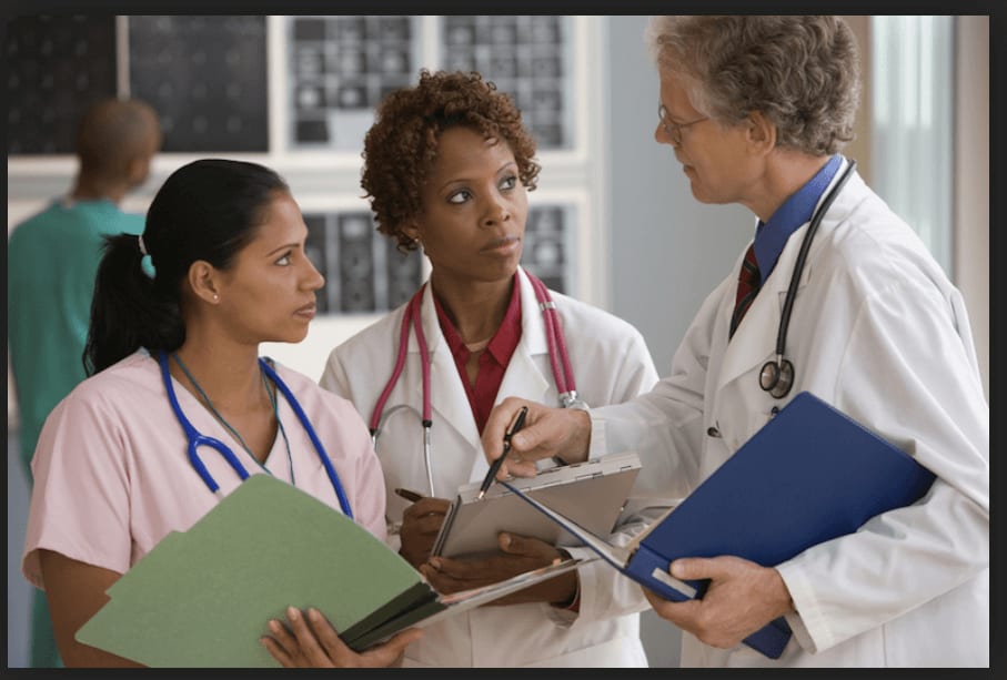 Three health care professionals discuss a patient.