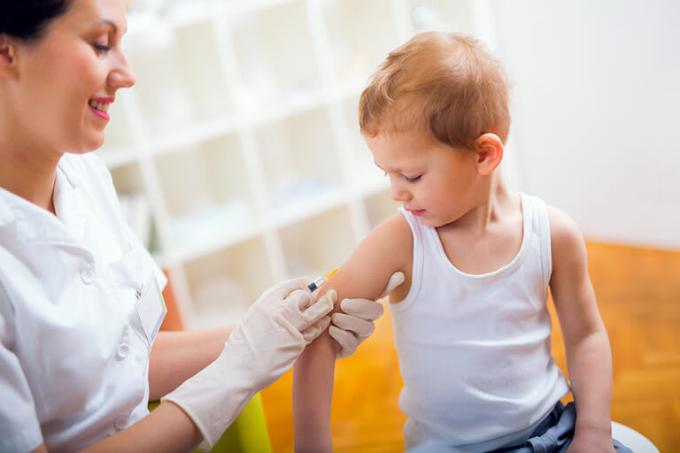A toddler receiving measles vaccine from a female nurse practitioner
