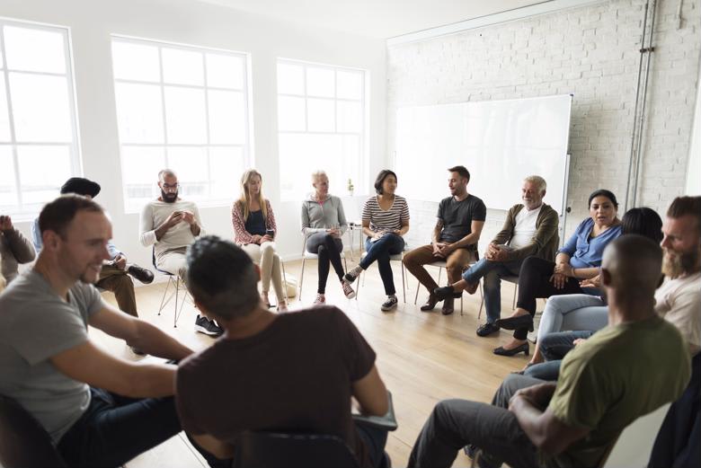 A counselor leads a group counseling session with adults.