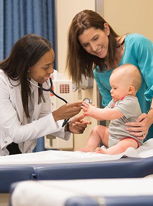 Female FNP holding stethoscope and a mom holding her infant
