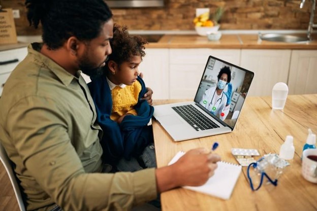 A parent and child talk with a caregiver via videoconference.