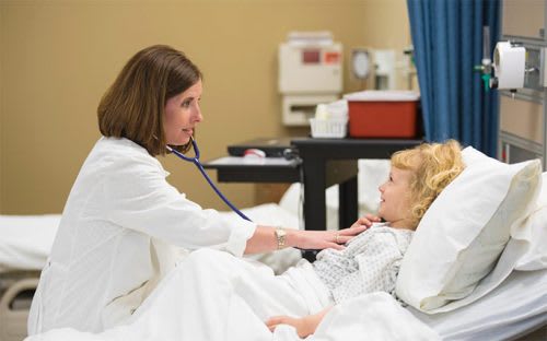 Female doctor examining a little blond haired girl with a stethoscope