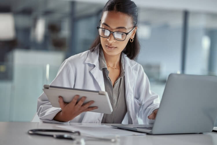 A clinical information specialist using a tablet and laptop.