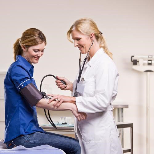 Female doctor in a white coat measuring blood pressure of a female patient