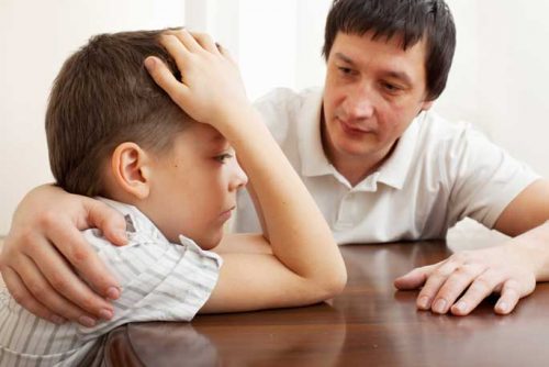 Father comforts sad son