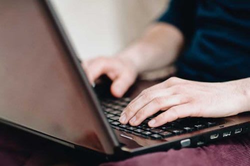 Pair of hands types on a laptop