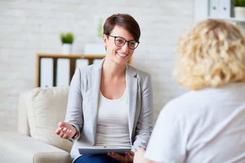 Female Counselor With Short Brown Hair and Glasses Smiling at the Client
