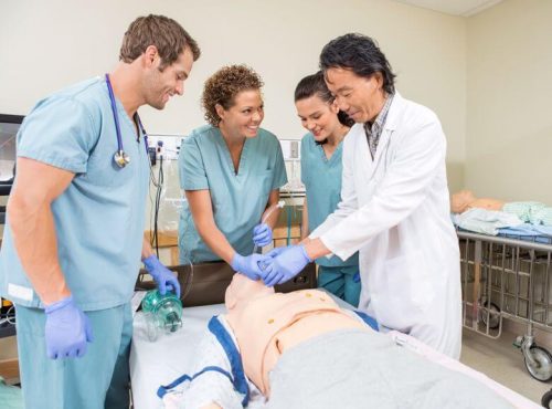A nursing professor helps students during a lab class.