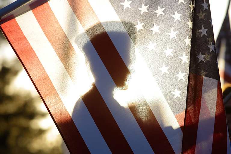 Silhouette of a soldier seen through the United States of America flag
