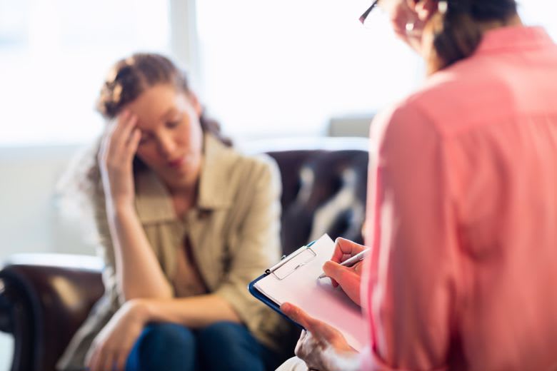 A counselor takes notes during a client appointment.