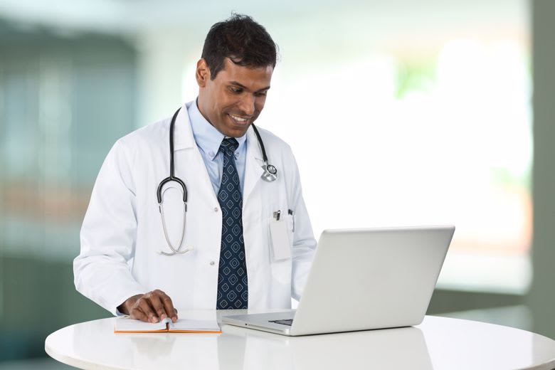 A nurse uses a laptop to conduct statistical analysis.