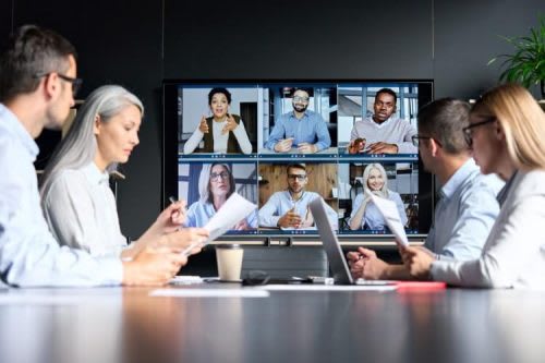 Remote and office-based employees meet via video screen.