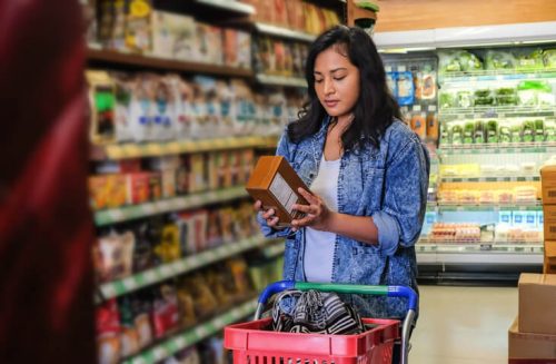 Woman reading cereal packaging in the supermarket.