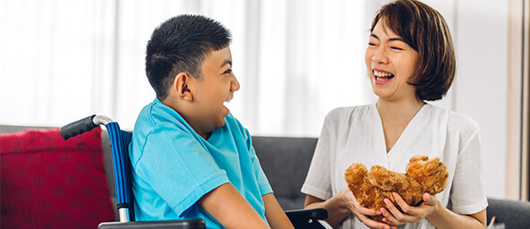 Woman holding a teddy bear laughs with a child