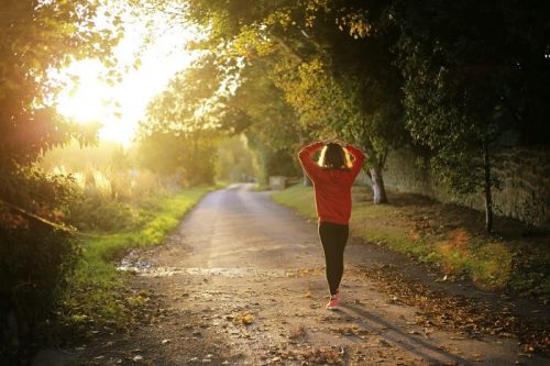 A woman walks outside to mitigate COVID-19 induced stress.