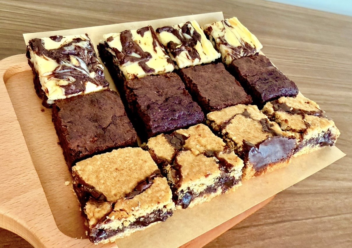 Assorted bars of cheesecake brownies, fudgy chocolate brownies, and chewy revel bars.