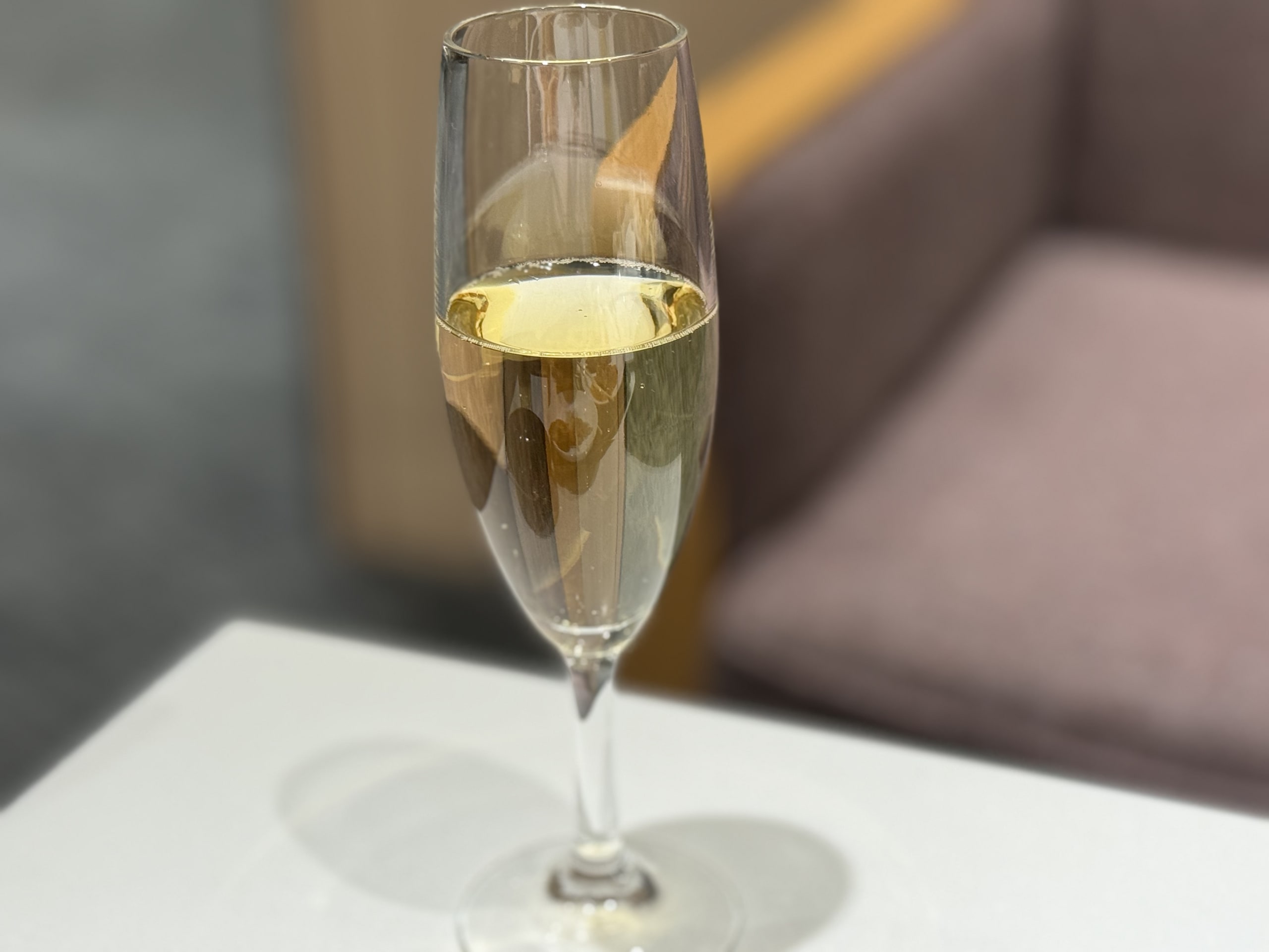白い机の上のシャンパングラス。背景に茶色のソファ。