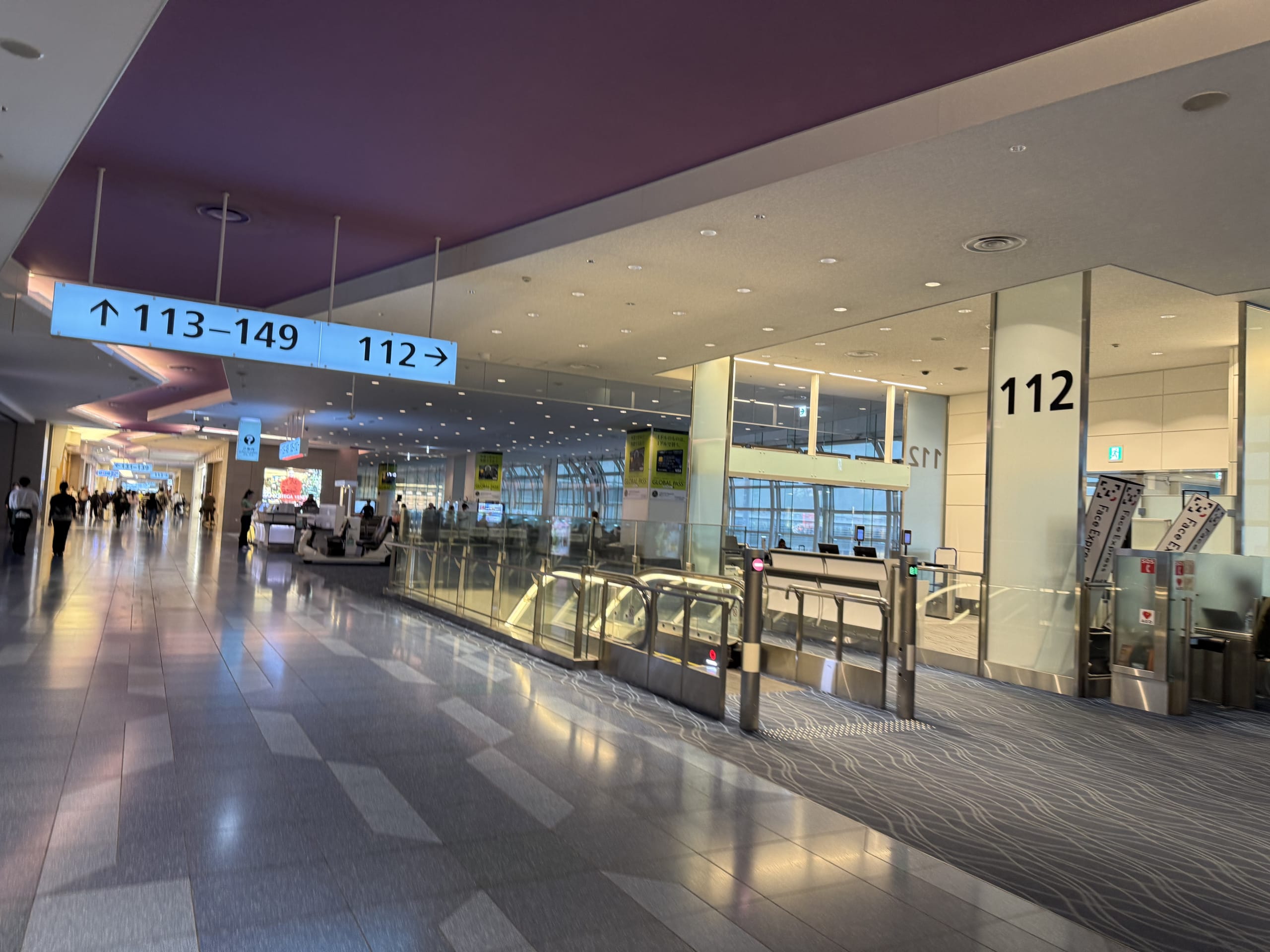 空港の出発エリア。112番ゲートの案内表示と右手に自動改札機がある。
