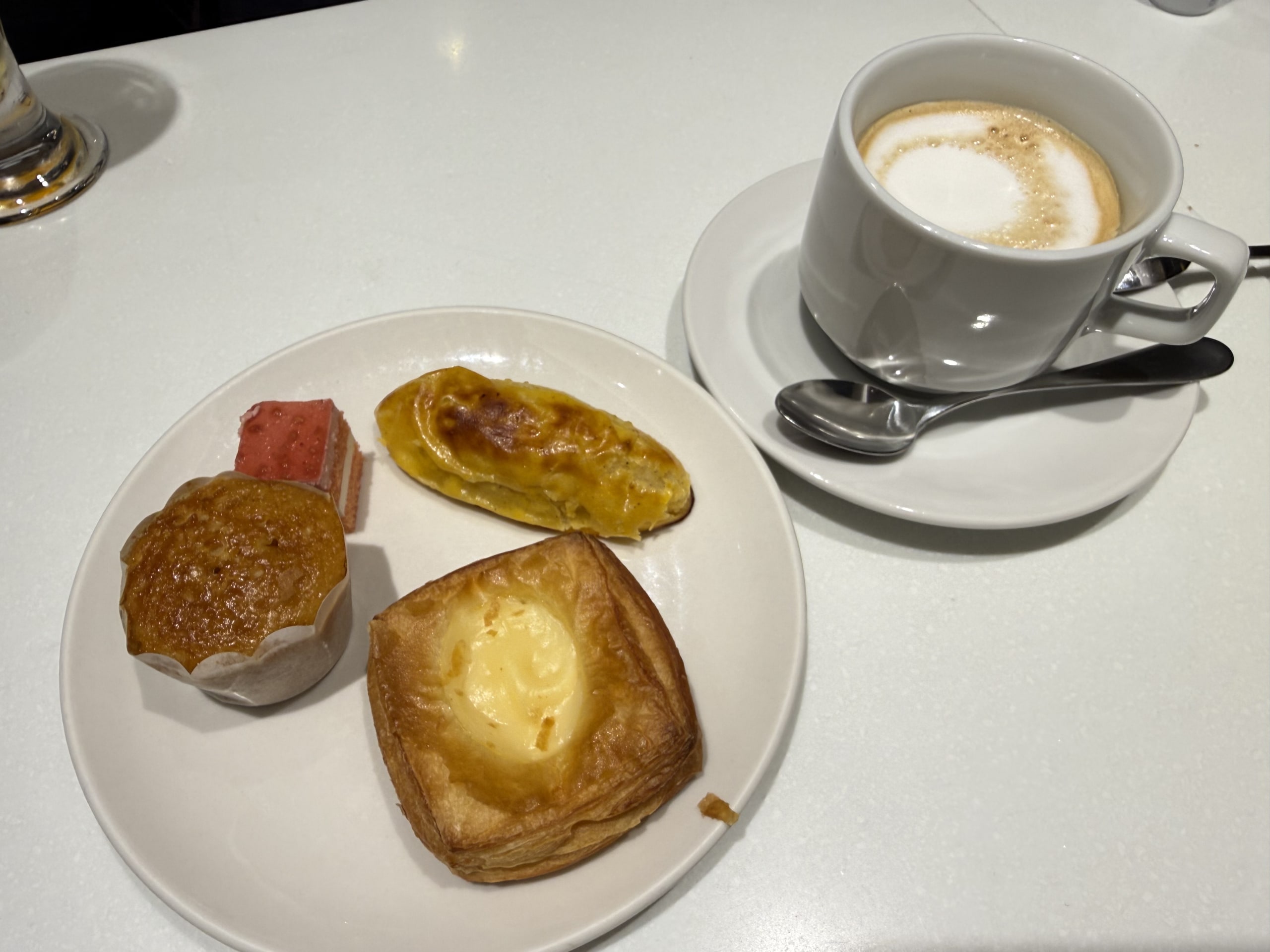 白い机上のカプチーノと4種の焼き菓子が乗った皿