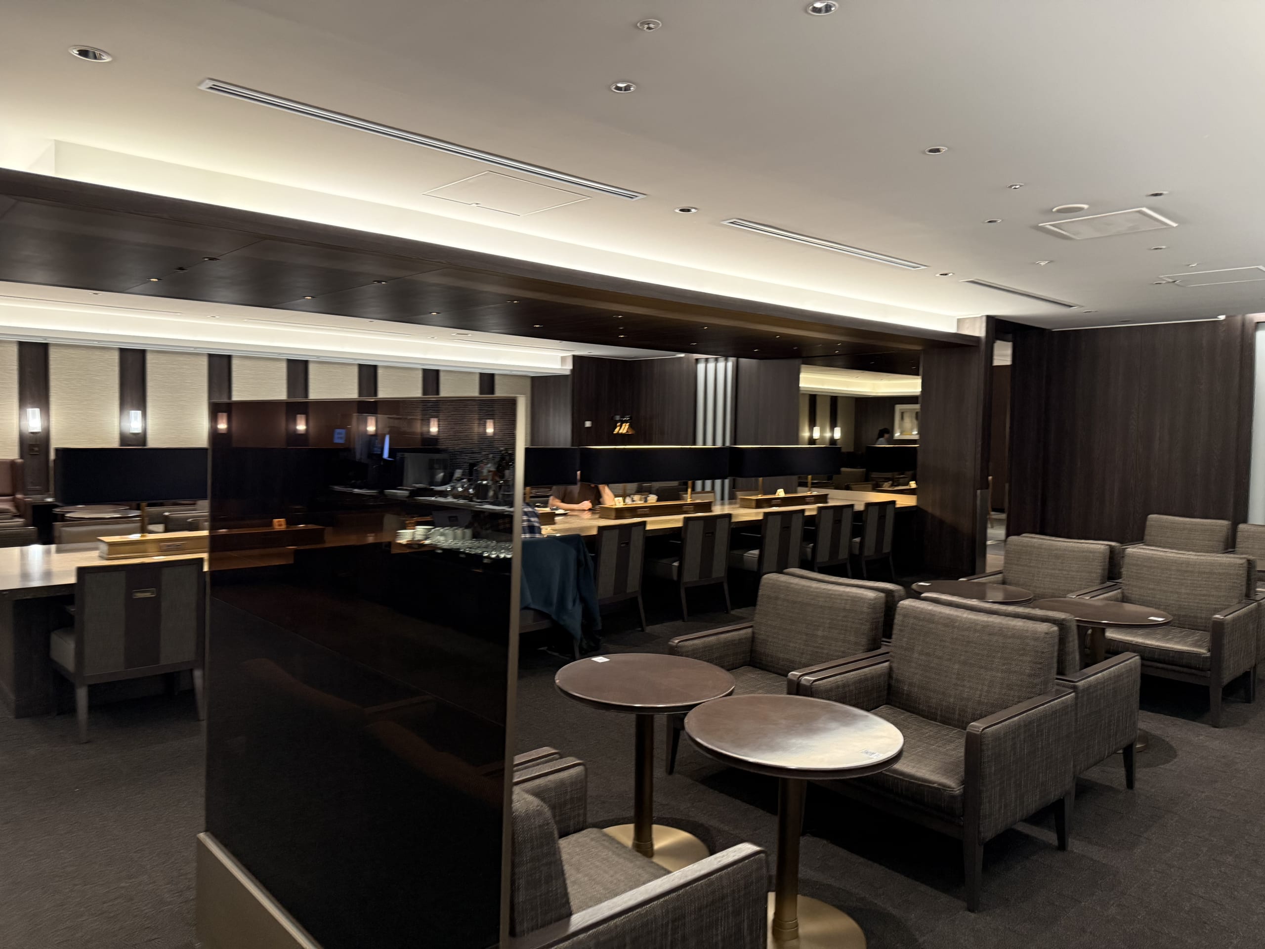 ダークブラウンを基調としたラウンジ。奥にデスクランプ付きの長机。