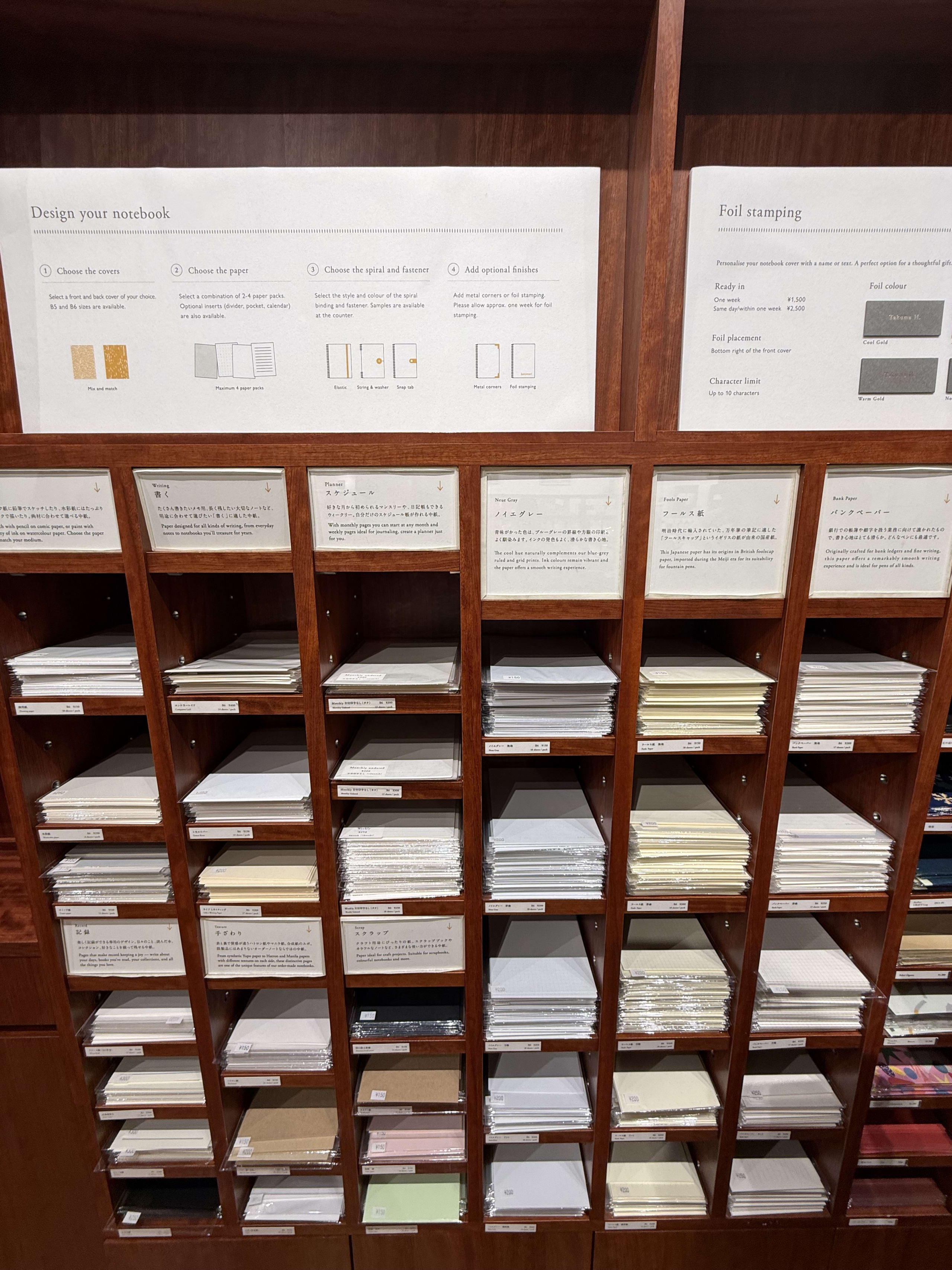 カスタムノート用の紙束が並ぶ木製の陳列棚