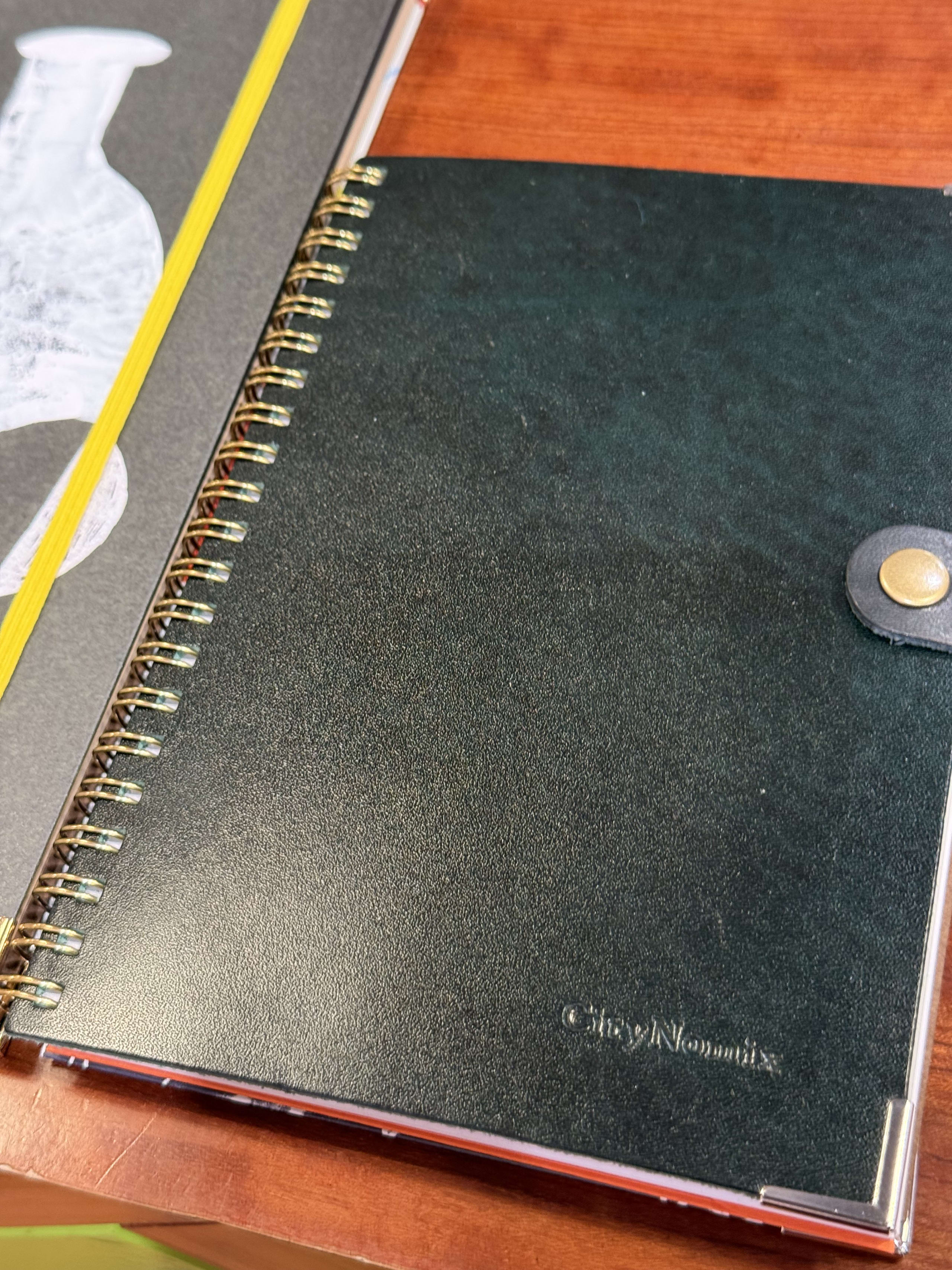 木製デスクの上の「CityNomix」型押し入り緑色ノート。