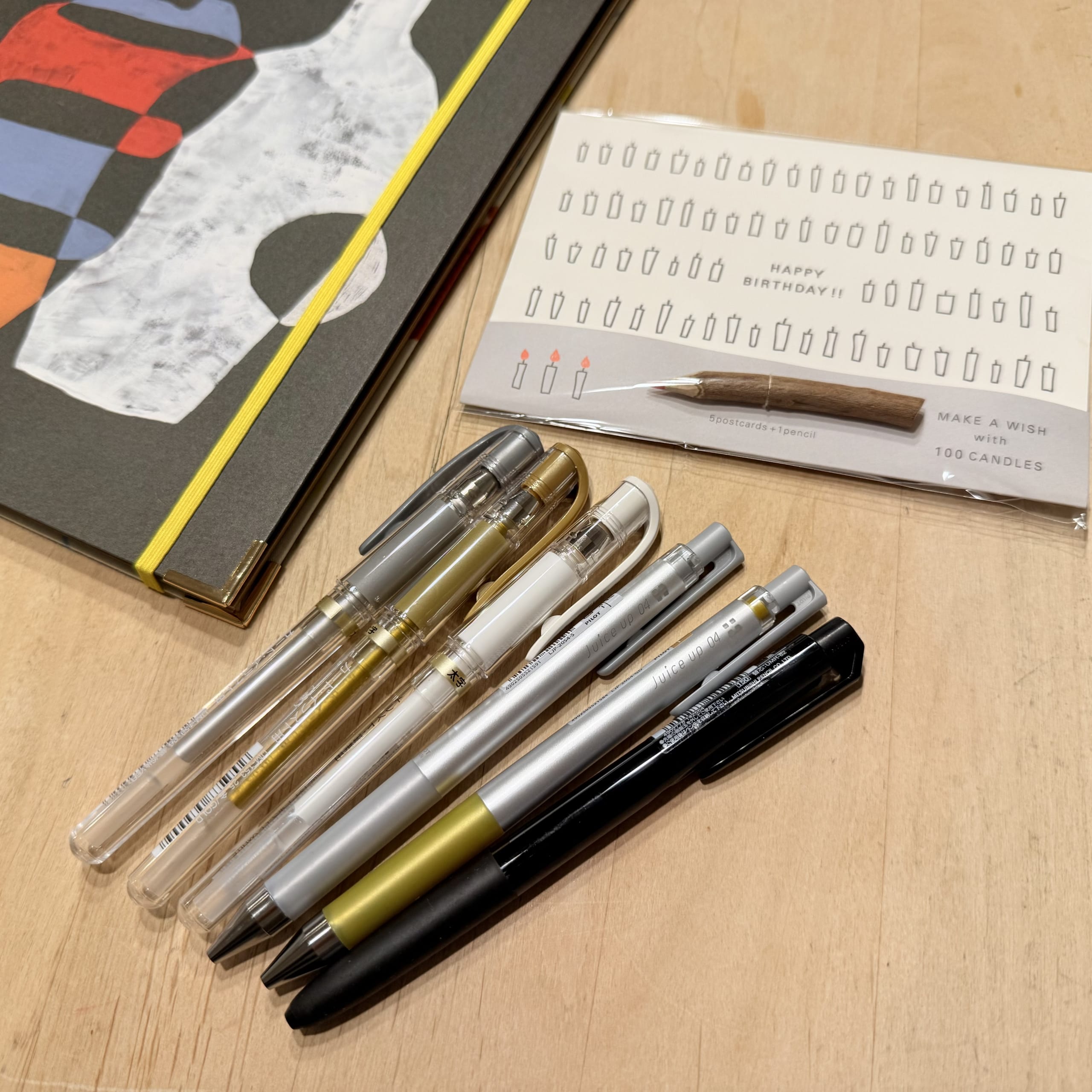 机上の金銀白のペン、ノート、小枝鉛筆付きカード。