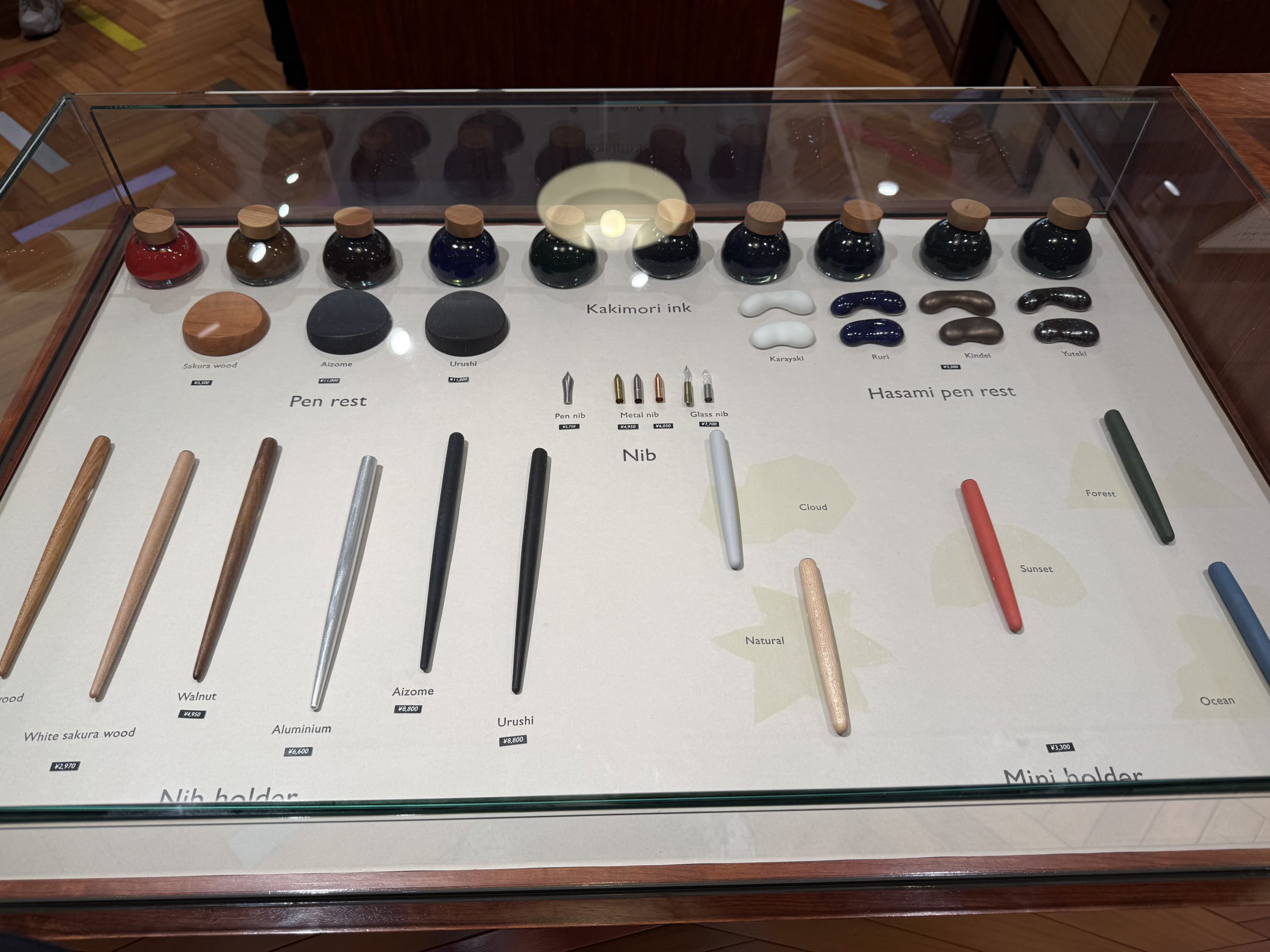 ガラスケースに並ぶカキモリのインク瓶、ペン先、多彩なペン軸とペンレストの展示。