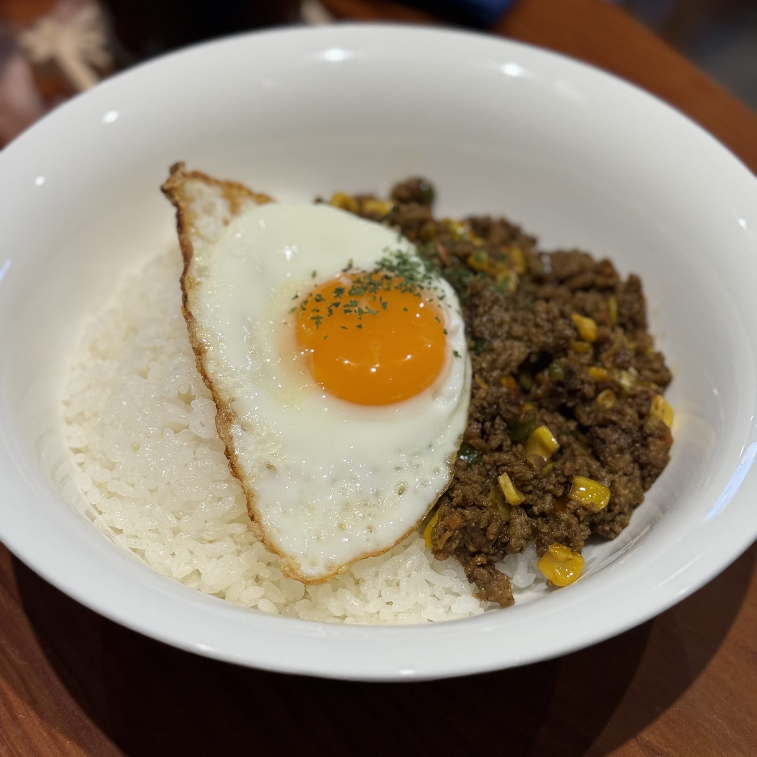 ご飯とキーマカレーの白い器。半熟の目玉焼きが乗る。