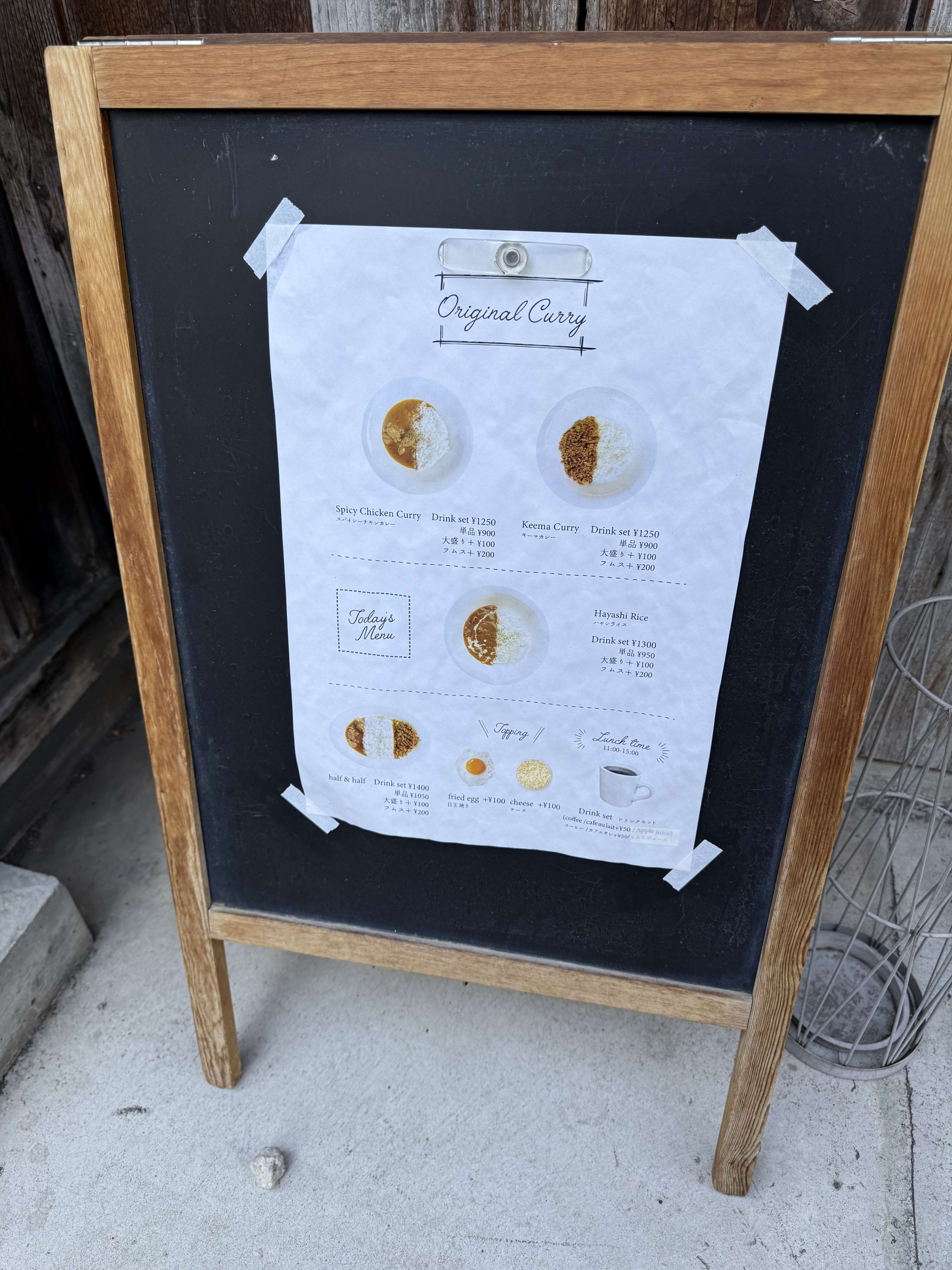古民家前の立て看板。カレーのメニュー表がテープで貼られている。