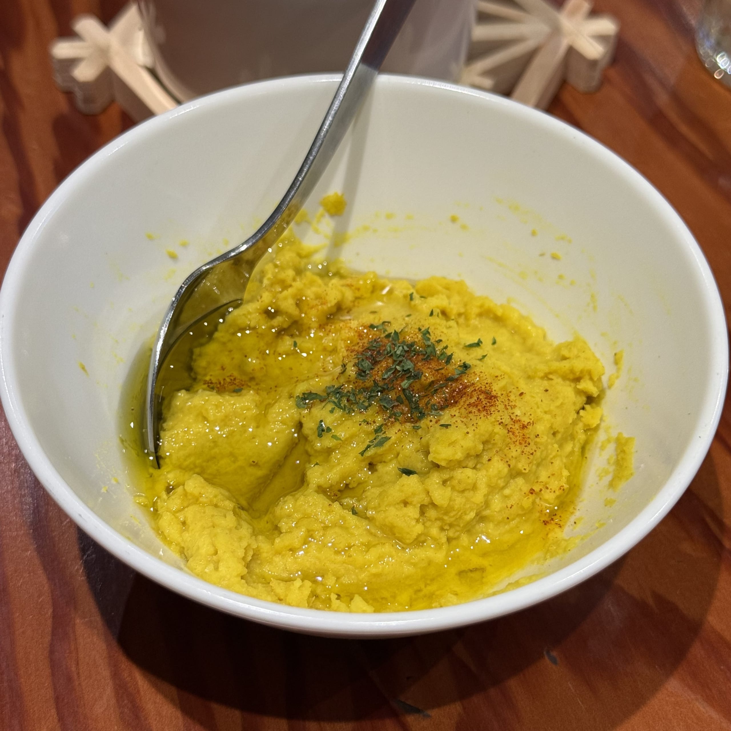 白いボウルに盛られた黄色いフムス。