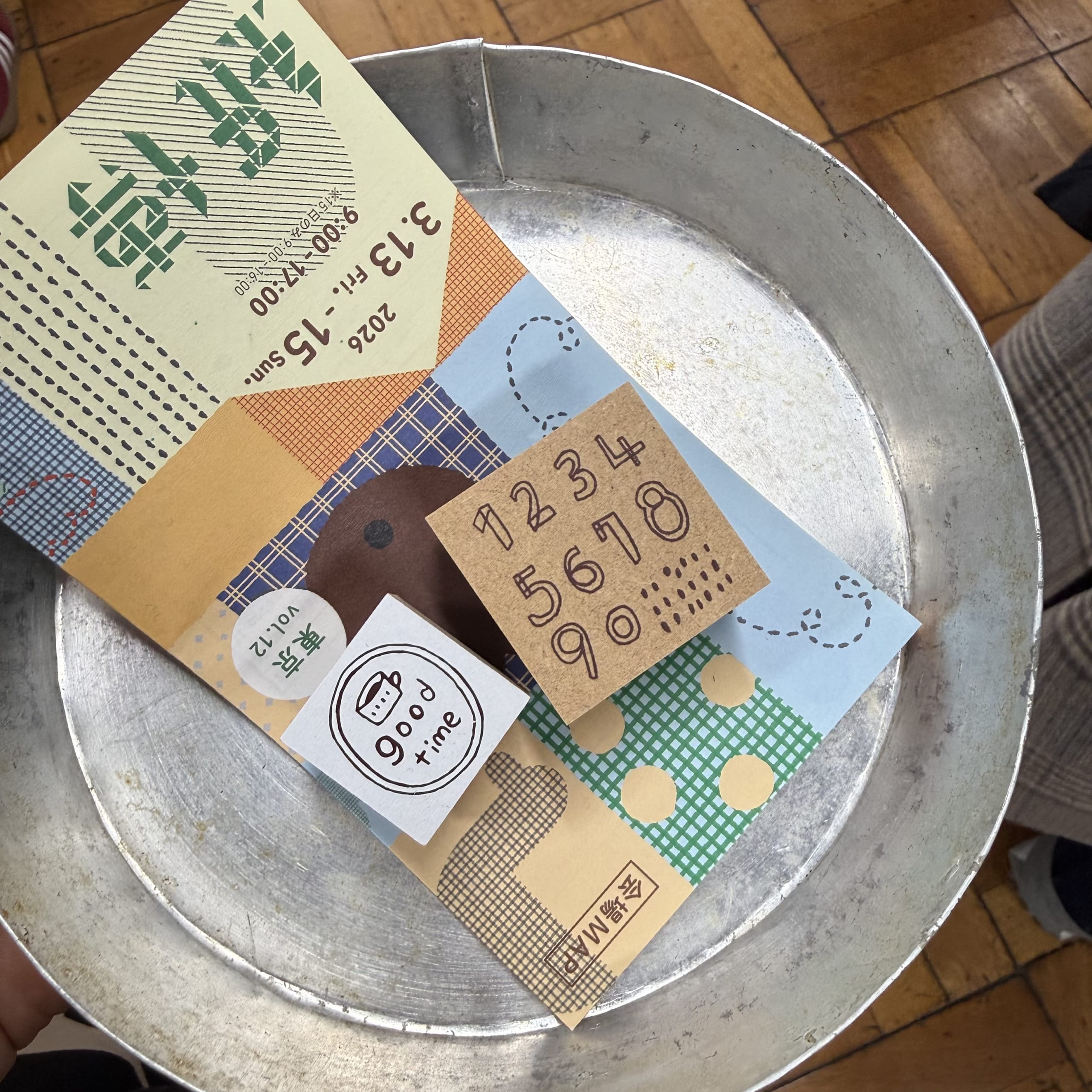 ブリキトレイに乗った紙博の会場マップと木製スタンプ。