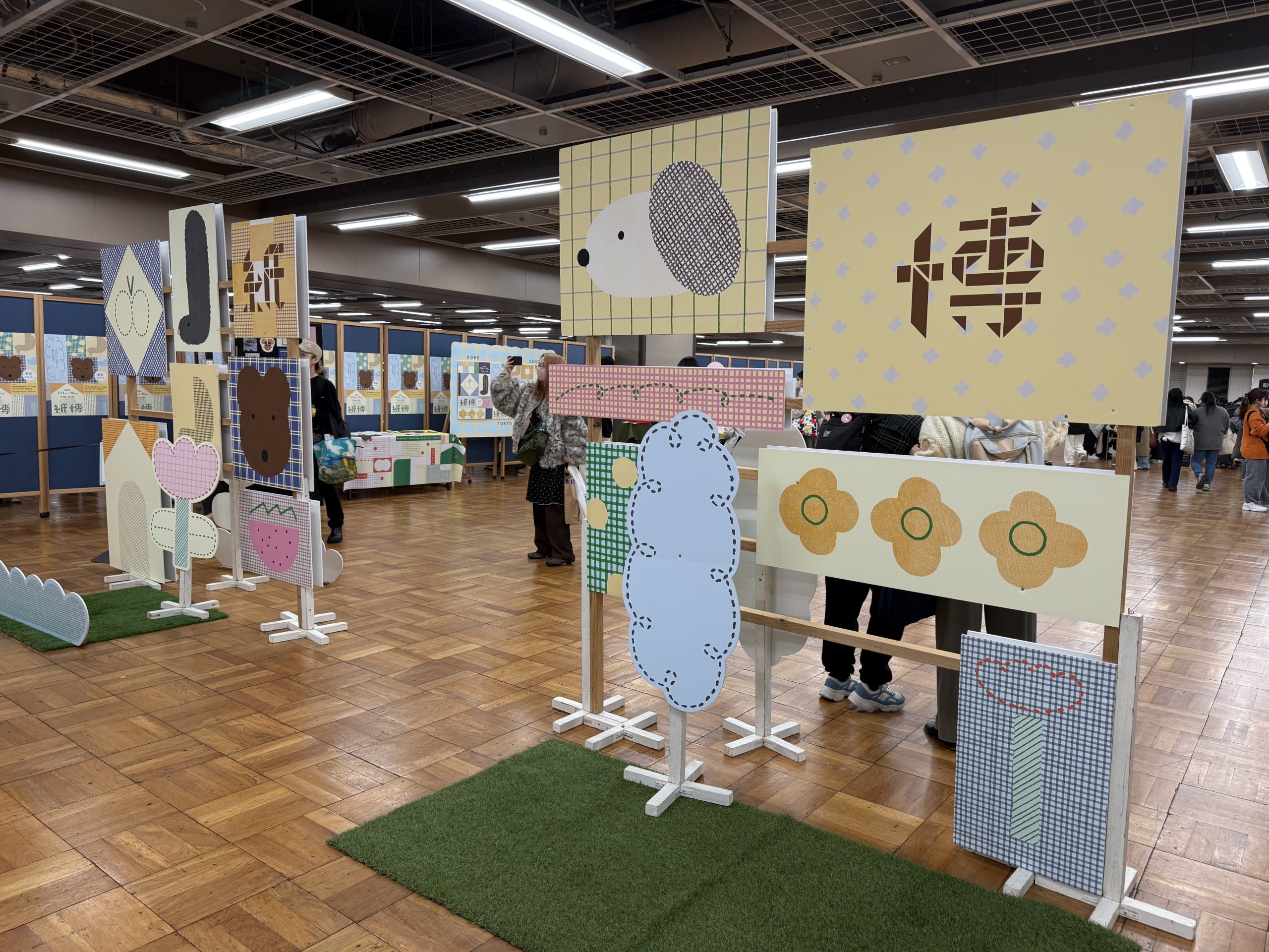 紙博の会場に並ぶ、犬や花が描かれた木組みのイラストパネル。